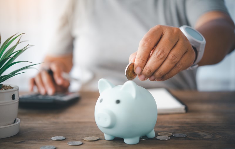 Como economizar para comprar uma casa | Foto de uma pessoa colocando moeda no cofrinho de porquinho | Estilo de Vida | Blog Alea