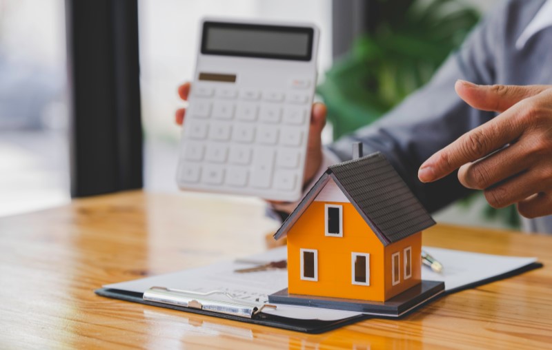 Qual é o valor do Imposto Predial e Territorial Urbano | Foto de um homem segurando uma calculadora | Como comprar uma casa | Blog Alea