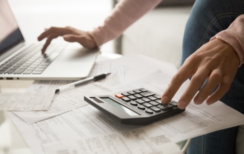 O que é uma análise de crédito | Foto de uma pessoa fazendo contas na calculadora | Como comprar uma casa | Blog Alea