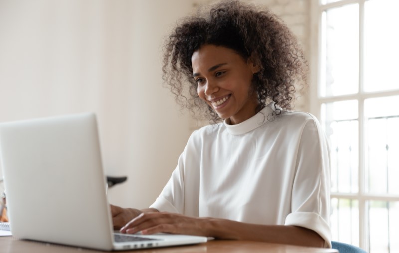 Score | Uma mulher sorrindo e pesquisando no computador | Como comprar uma casa | Blog Alea