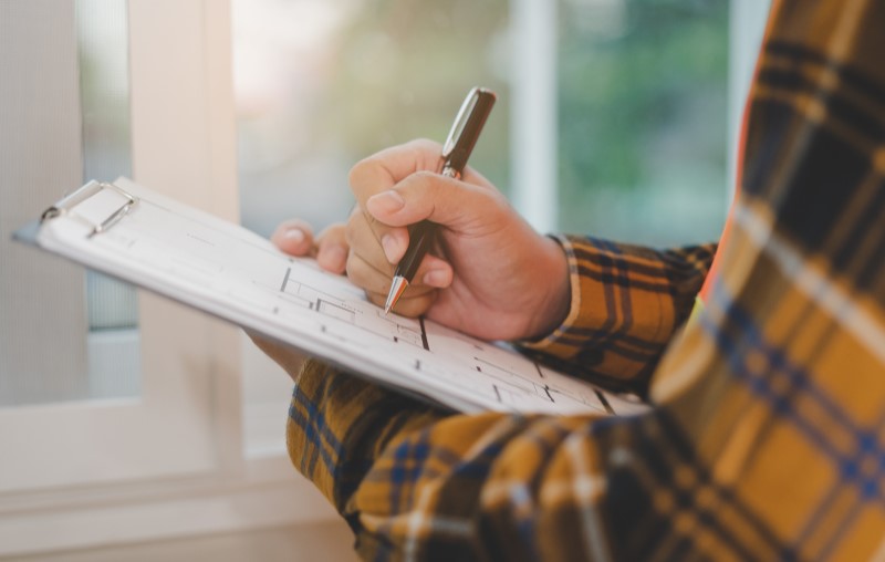 O que é vistoria de imóvel | Foto de uma pessoa fazendo anotações em uma prancheta | Como comprar uma casa | Blog Alea