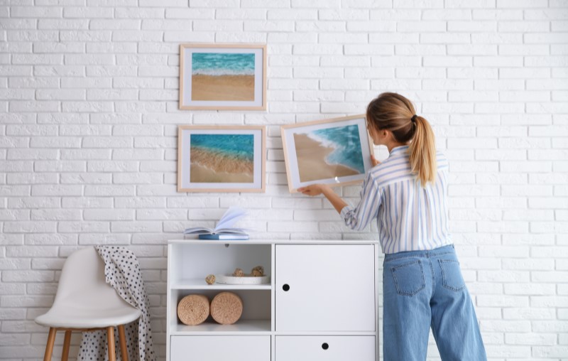 Tendências de decoração para 2023 | Foto de uma moça colocando quadros na parede | Estilo de vida | Blog Alea