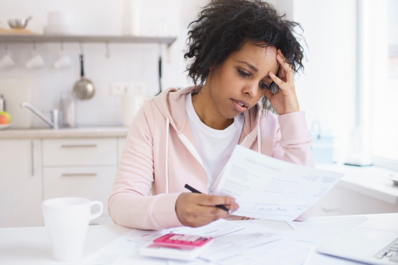 Como pagar imposto em atraso? | Foto de uma mulher preocupada com as contas | Como comprar uma casa | Blog Alea