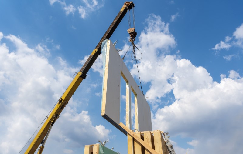 O que é wood frame | Foto de uma parede pré-fabricada sendo transportada em uma construção | Método Construtivo | Blog Alea