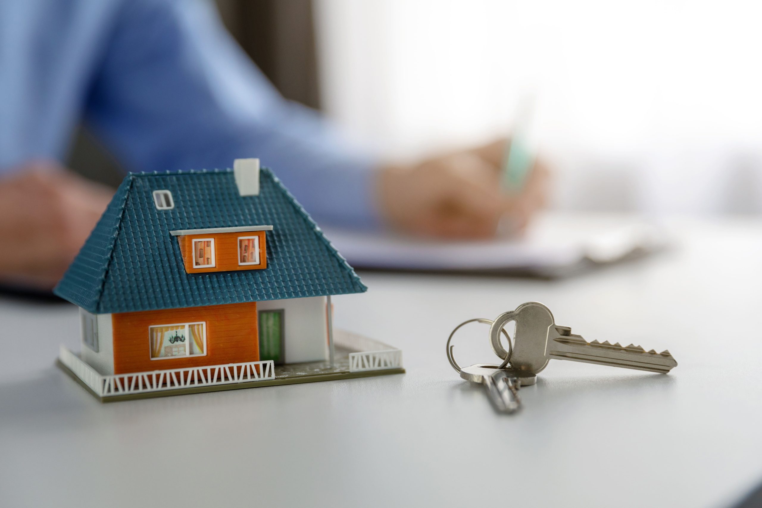 O que é o Minha Casa, Minha Vida 2023? | Foto de uma casa pequena e chaves, com uma pessoa ao fundo | Tudo sobre Casa Verde e Amarela | Blog Alea