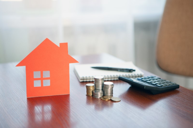 Quanto custa uma casa | Foto de uma casinha, moedas e uma calculadora sobre a mesa | Como comprar uma casa | Blog Alea