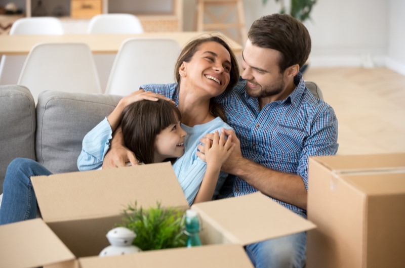 Como organizar uma mudança de casa? | Foto de um casal e uma criança feliz, com caixas de mudança ao redor | Estilo de Vida | Blog Alea