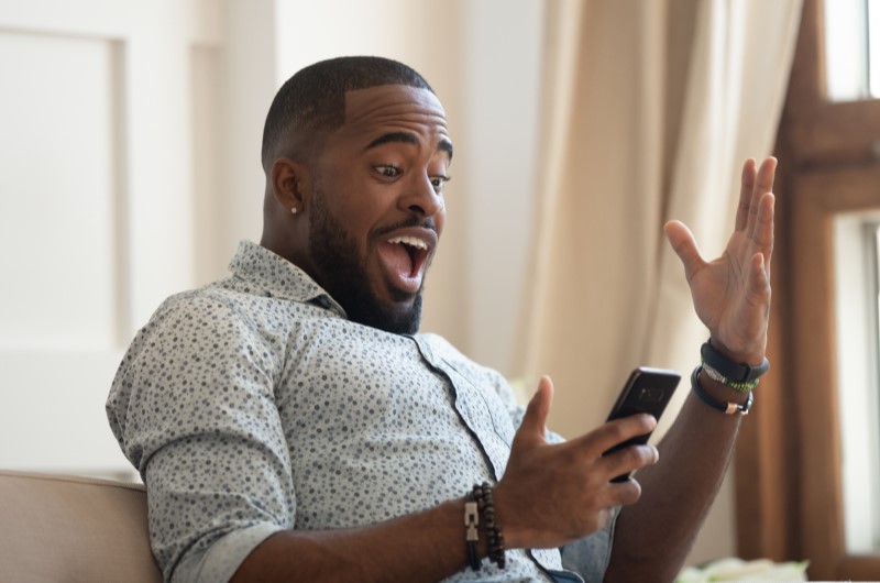 Procure promoções com cashback | Foto de um homem animado olhando para o celular | Estilo de vida | Blog da Alea