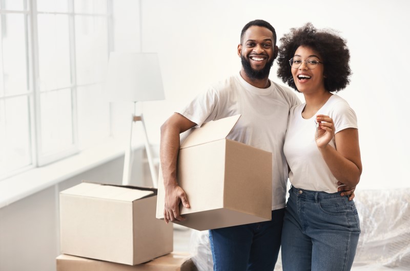 Verifique a casa nova e as regras em relação a mudança | Foto de um casal sorridente na casa nova, segurando uma caixa | Estilo de Vida | Blog Alea