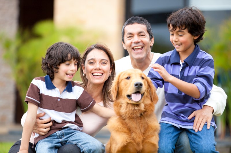 10 cuidados com animais de estimação durante as festas de fim de ano | Foto de uma família feliz e sorridente com um cachorro | Estilo de Vida | Blog Alea