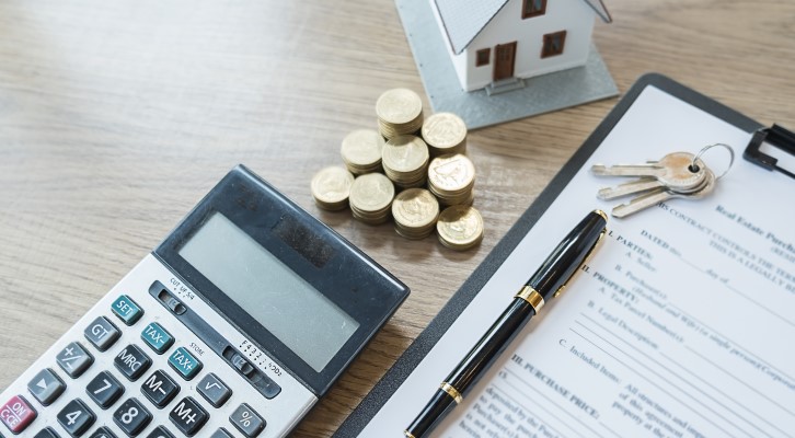 Foto de uma calculadora, moedas, casa e um contrato de financiamento | Amortização de financiamento | Como comprar uma casa | Blog Alea