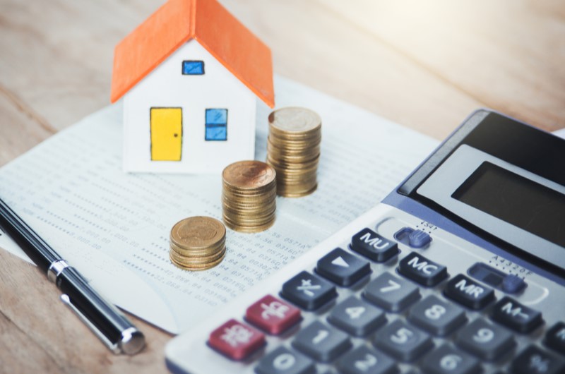 Custo de vida da cidade Três Lagoas | Foto de uma calculadora, uma casinha, moedas e um papel e caneta | Estilo de Vida | Blog Alea