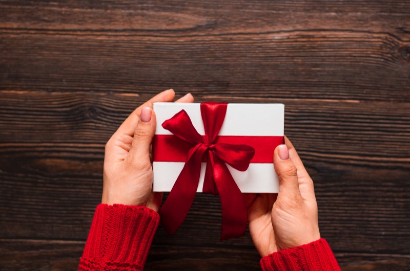 Ideias de presentes de Natal acessíveis | Foto de uma pessoa segurando um presente de Natal | Estilo de Vida | Blog Alea 
