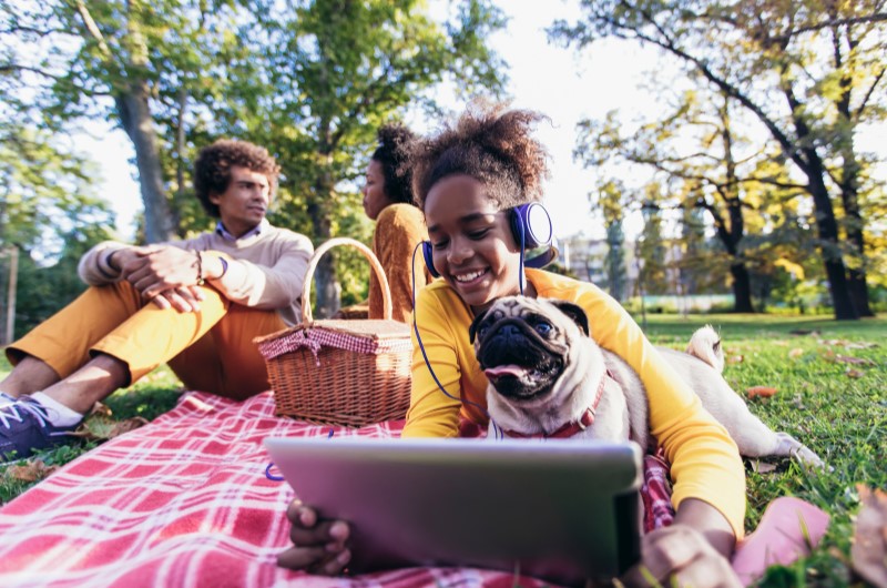 Ração e petiscos | Foto de uma família fazendo um piquenique no parque, com um cachorrinho | Estilo de Vida | Blog Alea