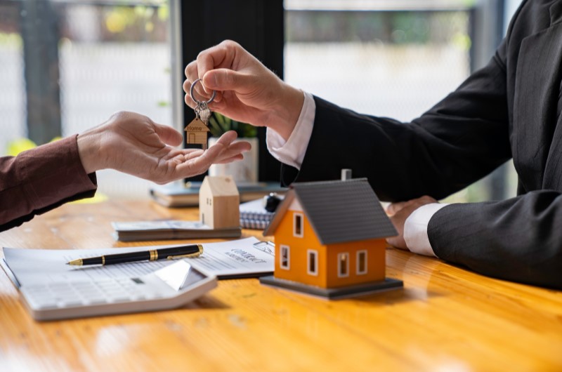 Como funciona o financiamento da Caixa? | Foto de um corretor de imóveis entregando uma chave a um cliente | Como comprar uma casa | Blog Alea