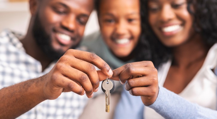 Comprar ou alugar uma casa: 6 motivos para comprar um imóvel | Foto de uma família feliz segurando a chave da casa própria | Como comprar uma casa | Blog Alea